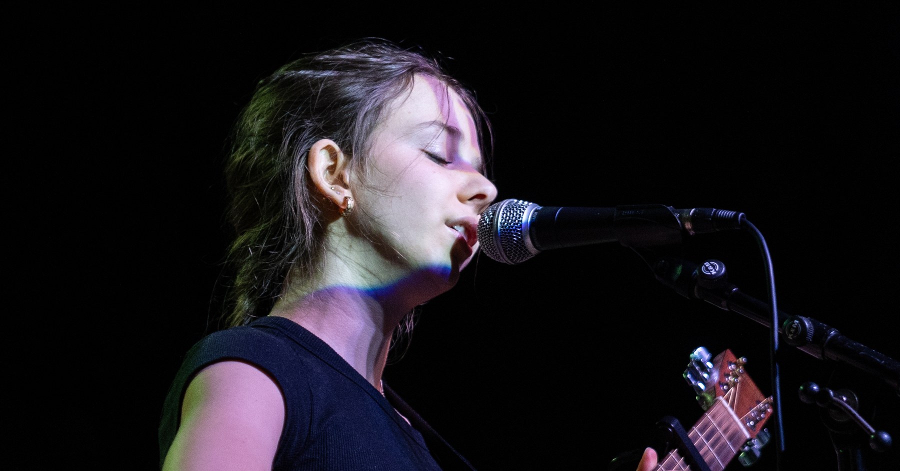 A Quarter Bend voice student singing on stage with eyes closed at the microphone
